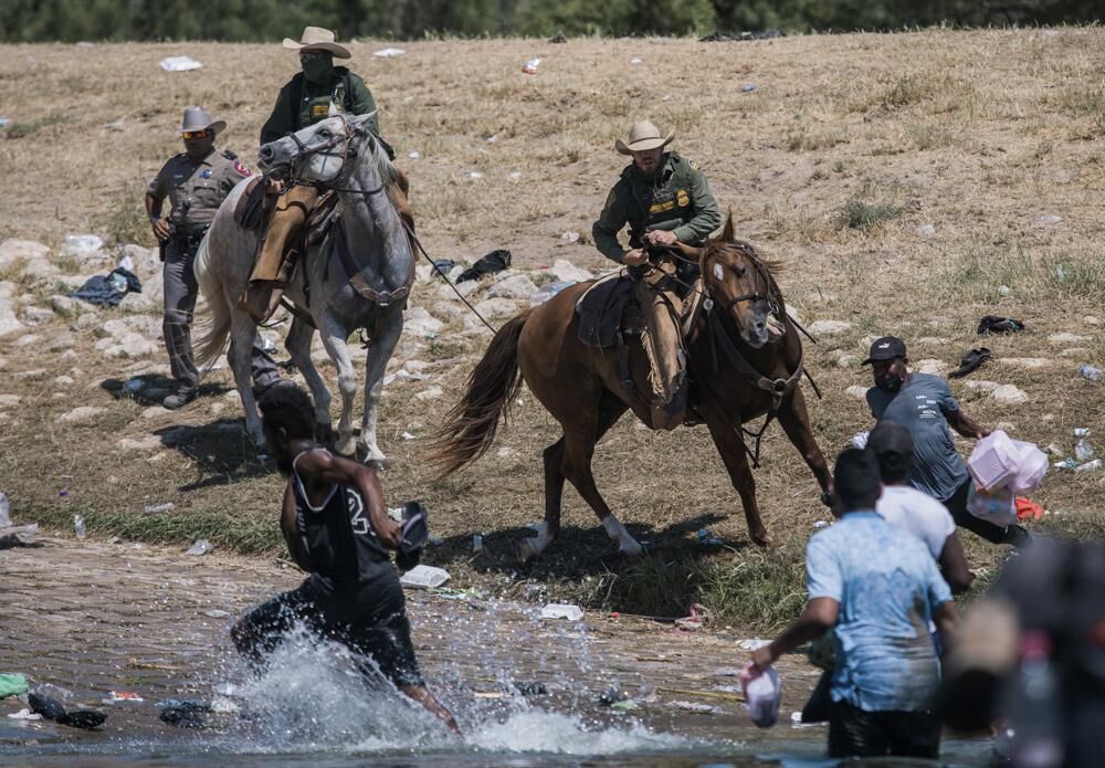 Mounted officers near migrants at border